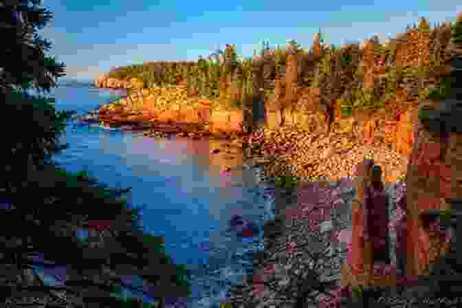 A Dramatic View Of Otter Cliff's Sheer Granite Face Illuminated By The Warm Glow Of Sunset, With The Crashing Waves Below And A Distant Lighthouse In The Background. Glistening Sunsets (A Mount Desert Island 5)